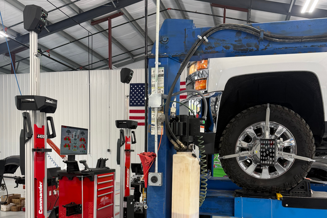 Auto repair shop with a vehicle lifted on a blue hoist, wheel visible, and tools in the foreground