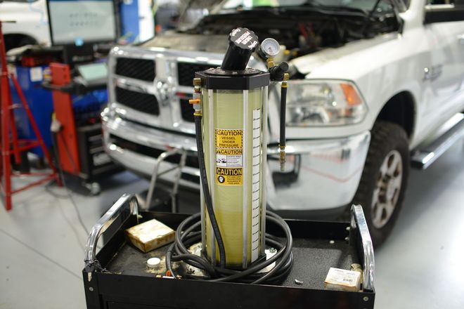 Hydraulic jack in a garage, with a white pickup truck in the background