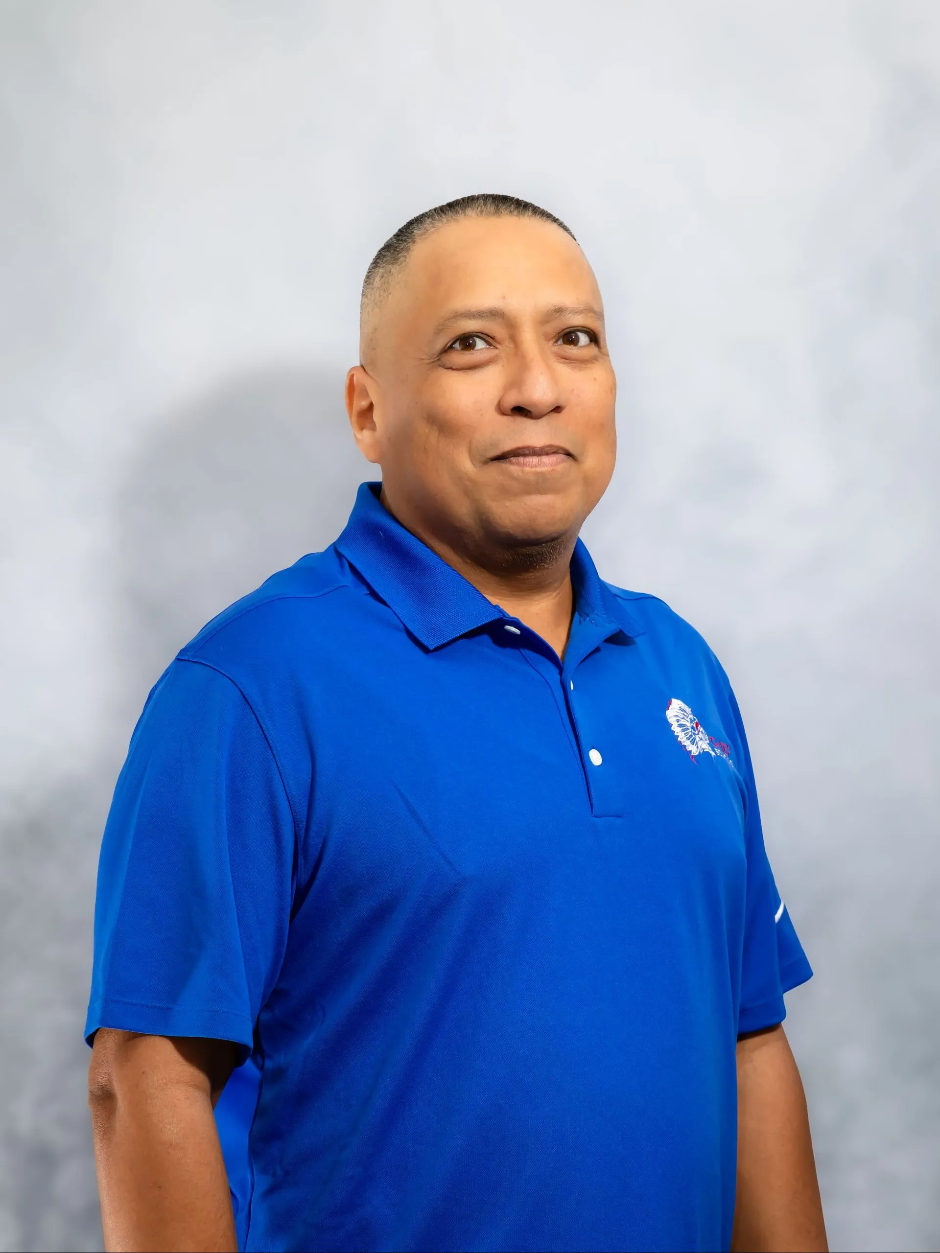 Man in blue polo shirt smiles, posing for a photo.