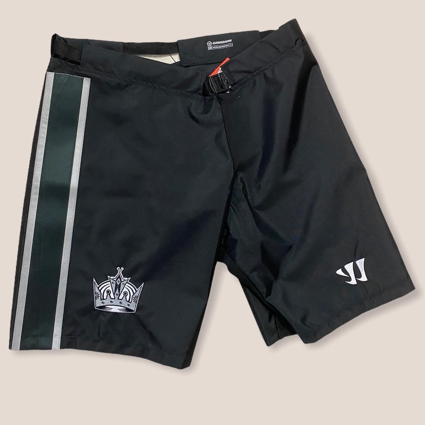 Black sports shorts with white stripes and logos on a plain background