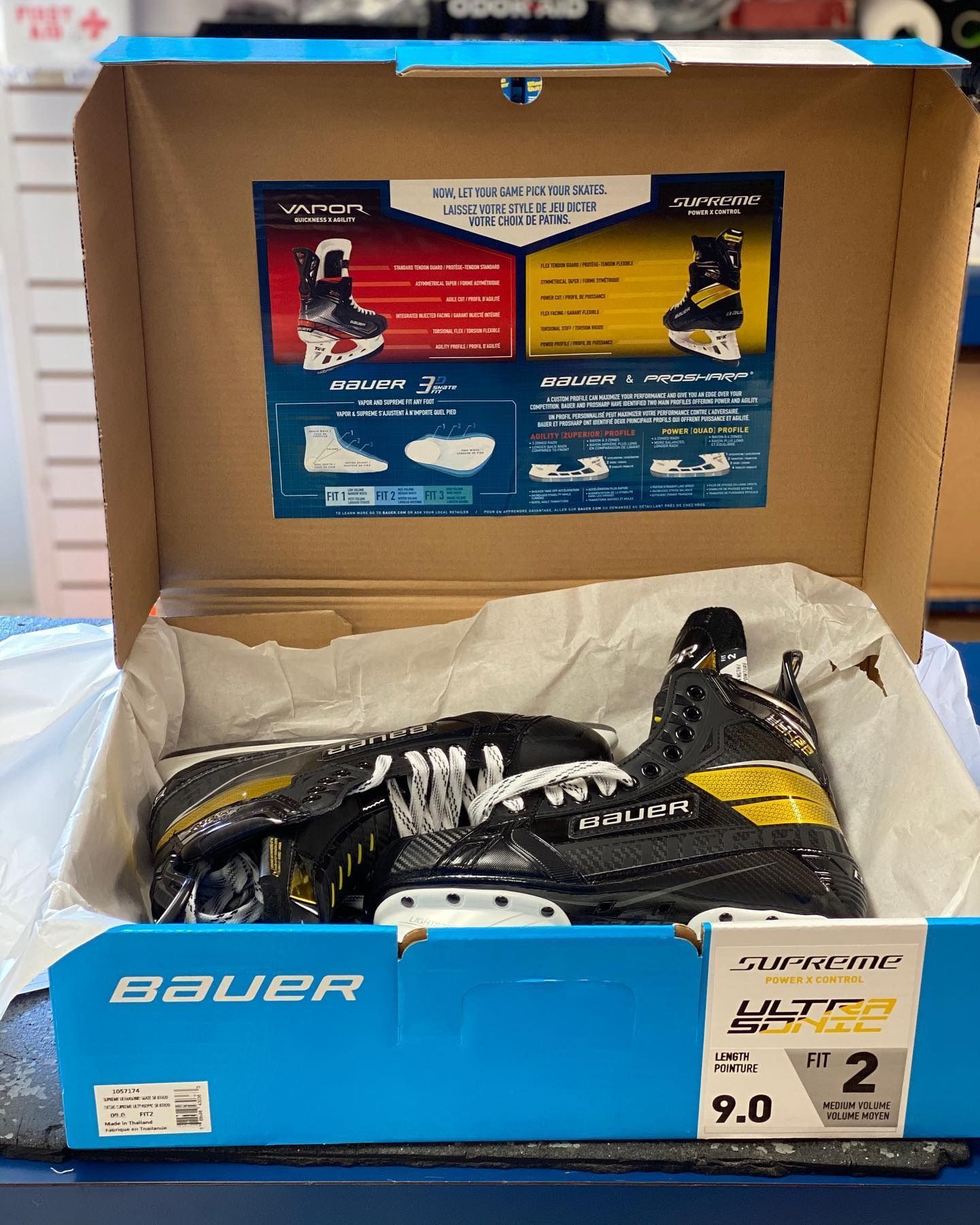 Black Bauer hockey skates in an open blue and tan shoebox with tissue paper