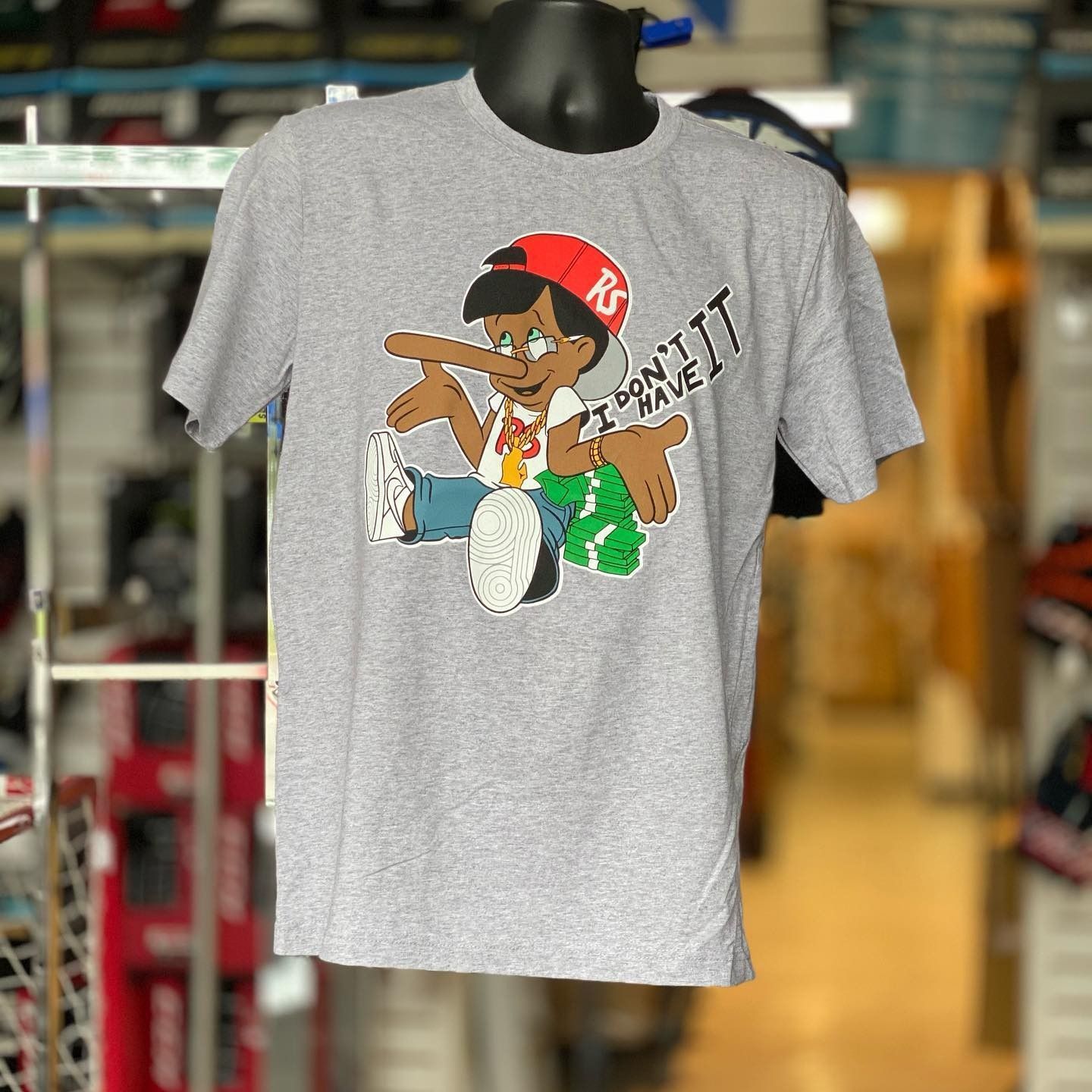 Gray T-shirt with a colorful cartoon drummer graphic hanging in a clothing store