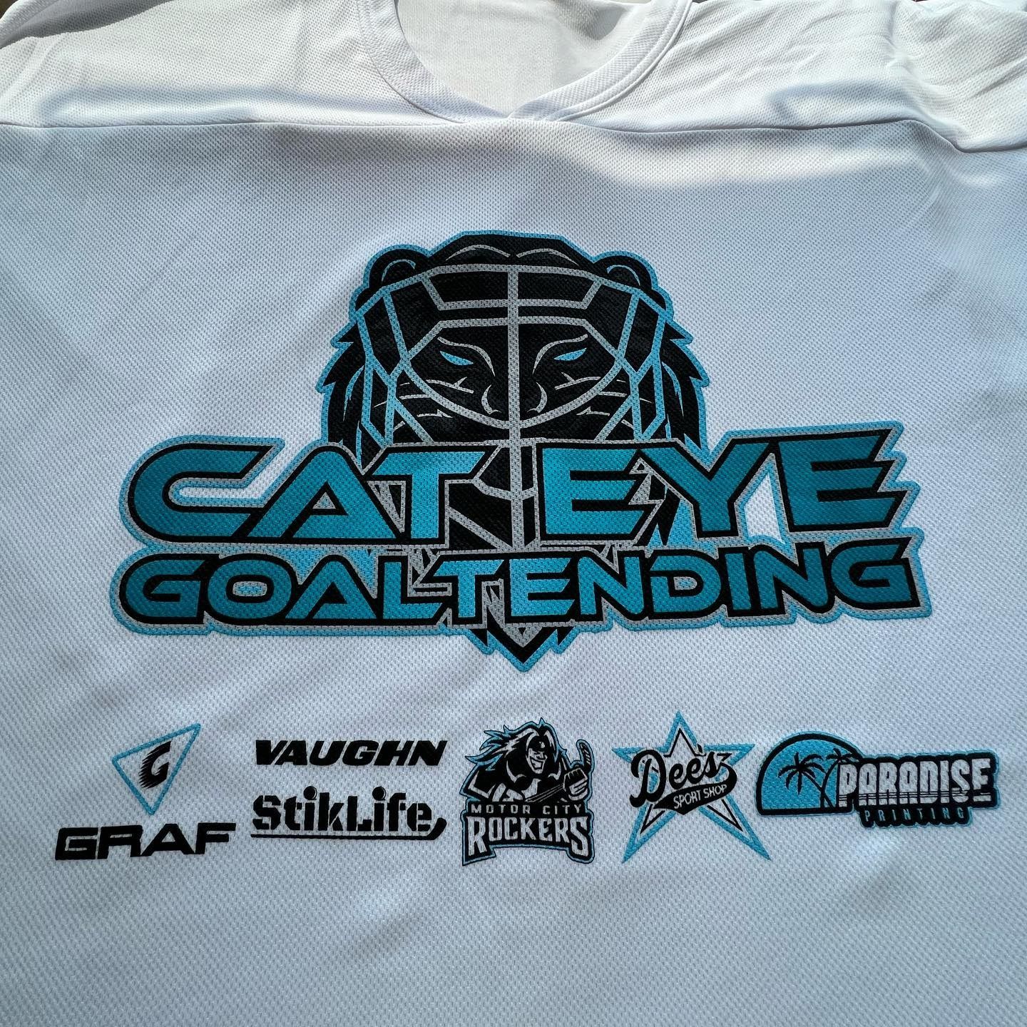 White sports jersey with a black-and-blue cat logo and “CAT EYE GOALTENDING” sponsor logos.