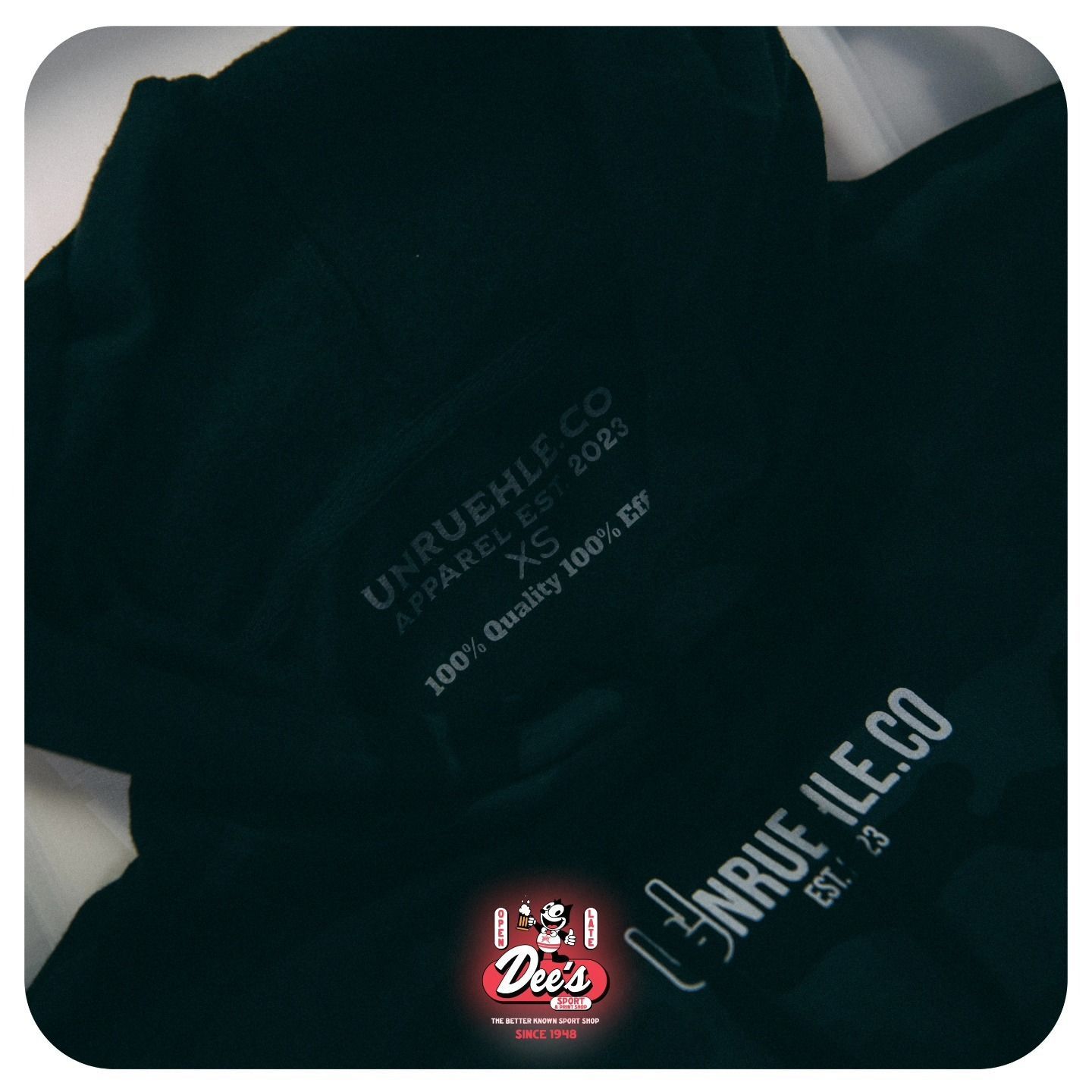 Close-up of a black T-shirt with white printed text and a small red logo on the chest.