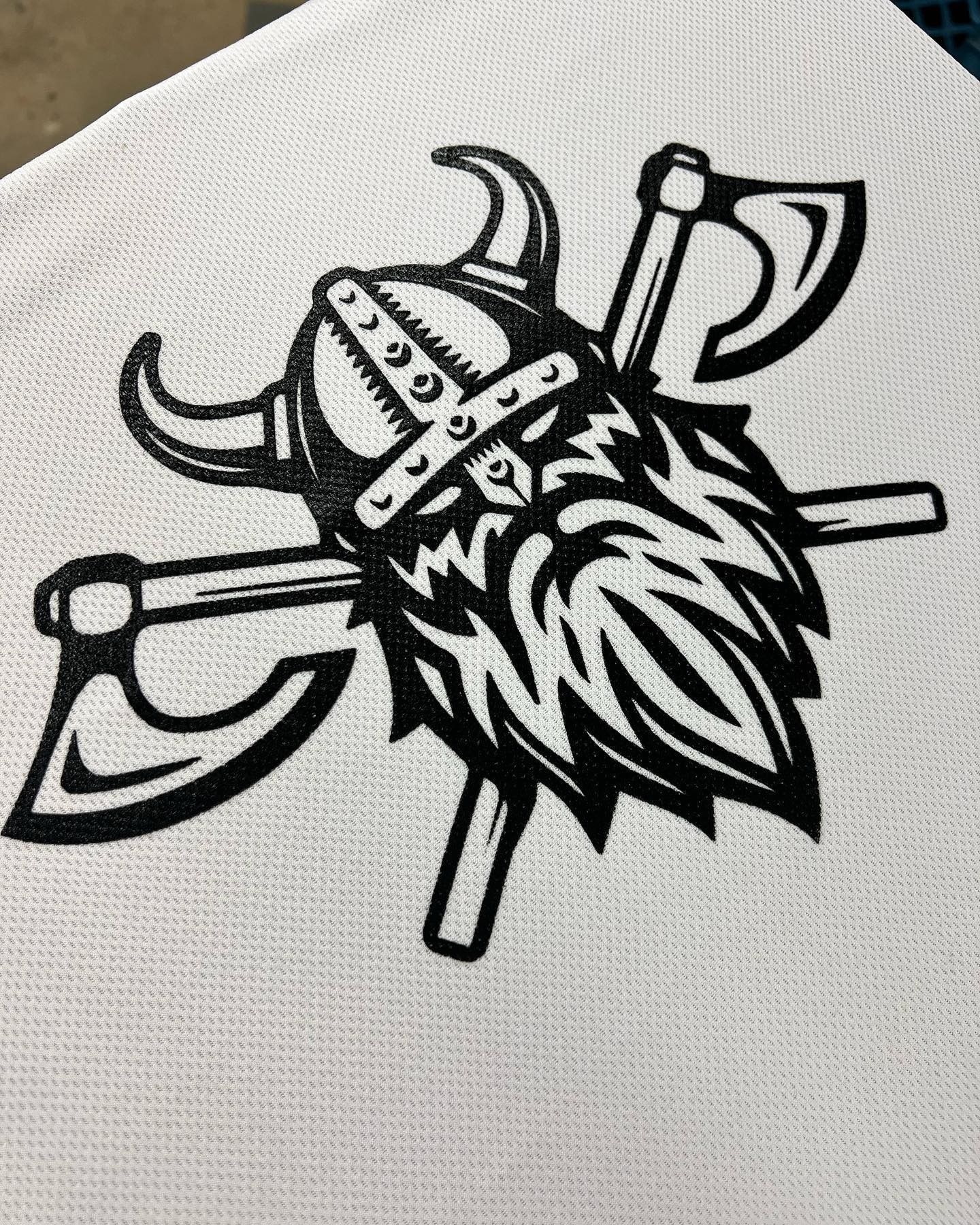 Black Viking helmet and crossed axes tattoo-style graphic on white fabric