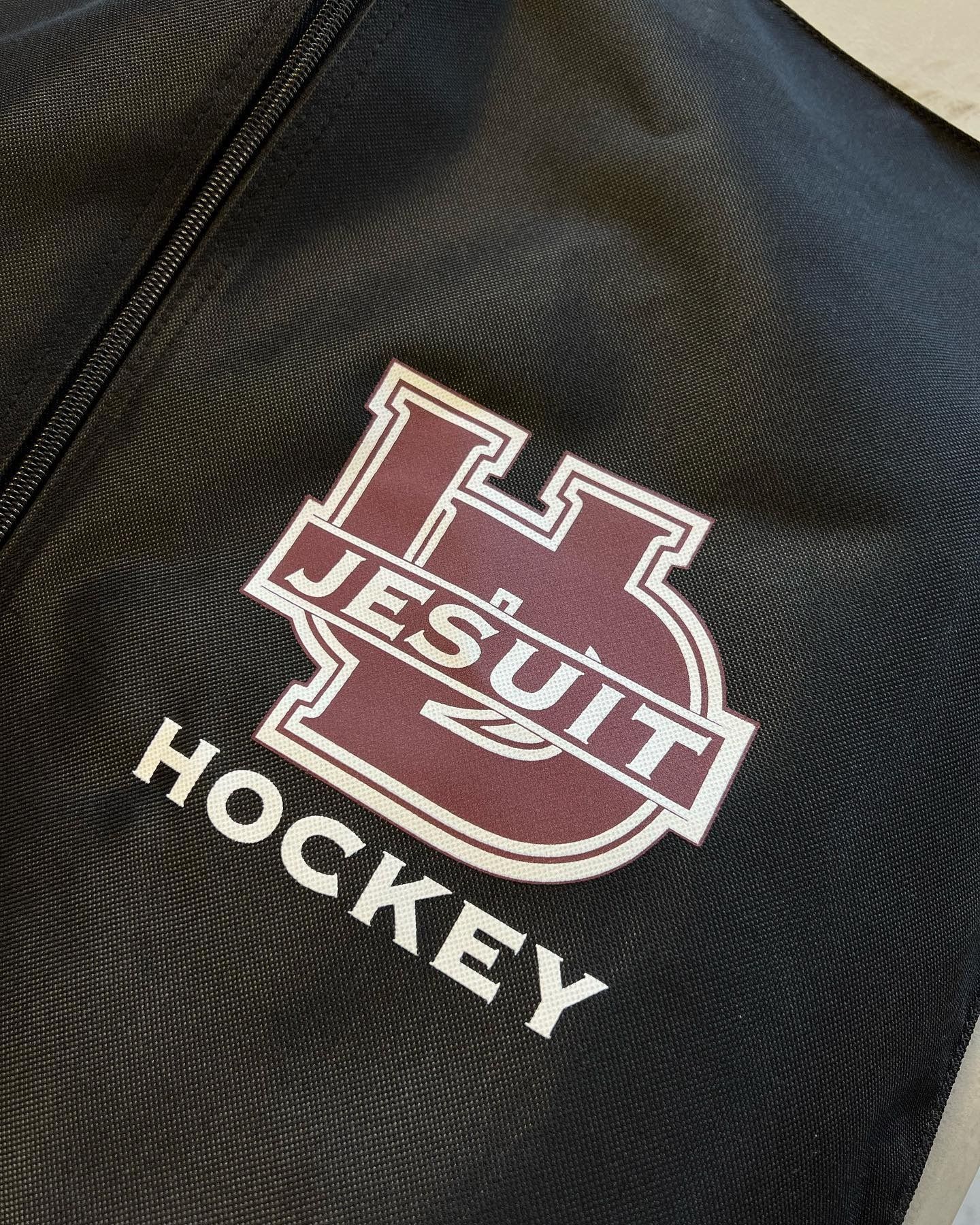 Maroon Jesuit Hockey logo embroidered on black fabric