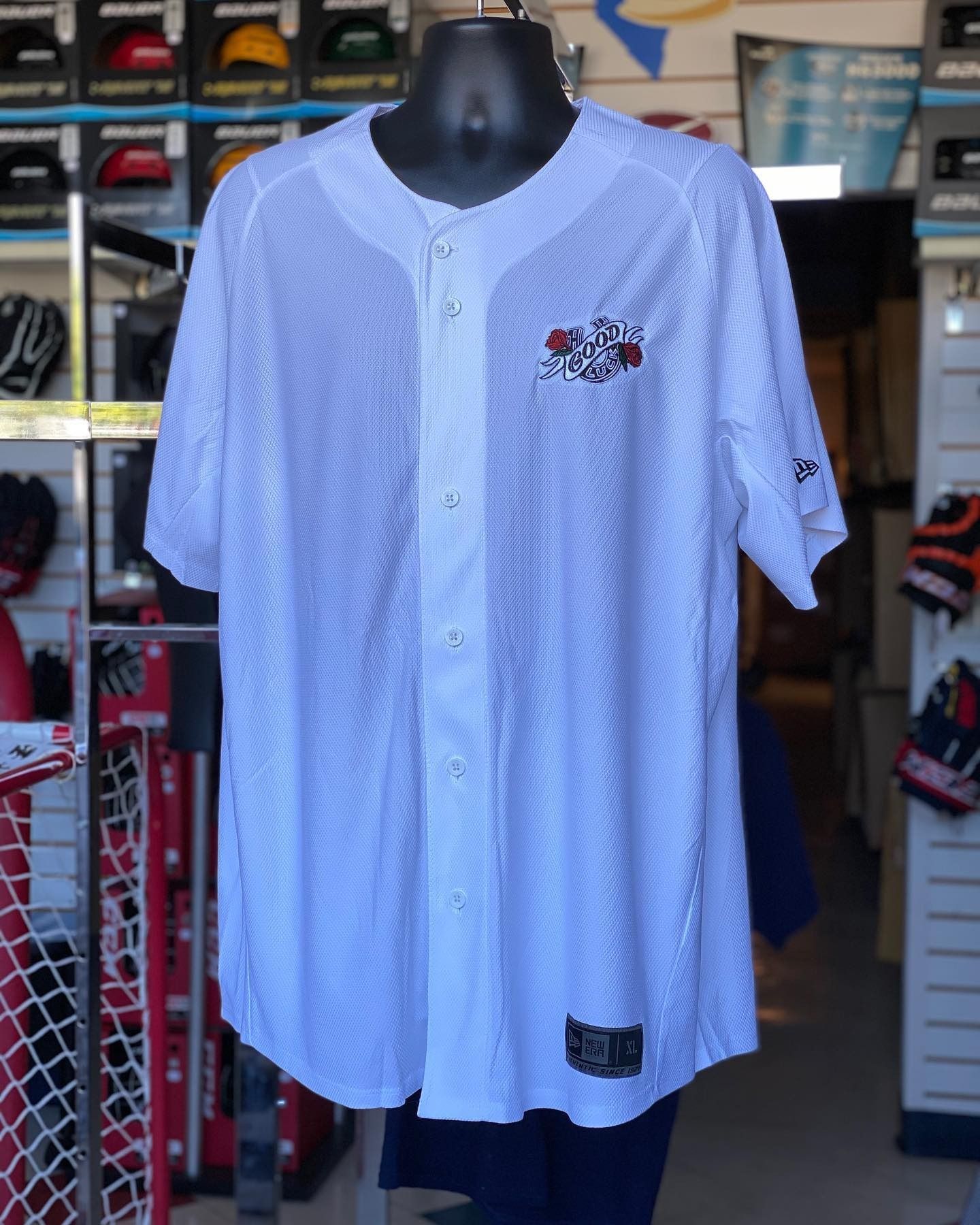 White sports jersey displayed on a black mannequin in a shoe store.