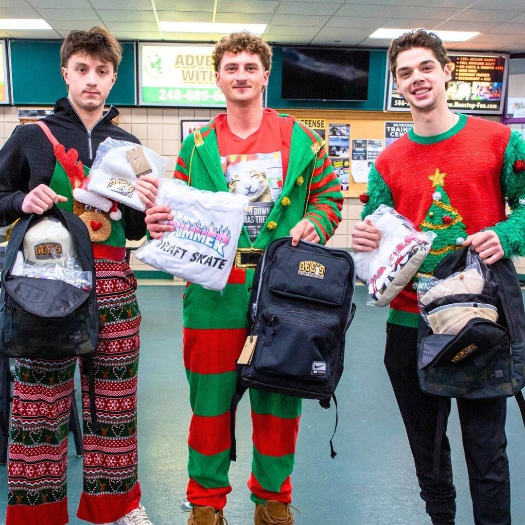 Three people in festive Christmas outfits holding shopping bags inside a store