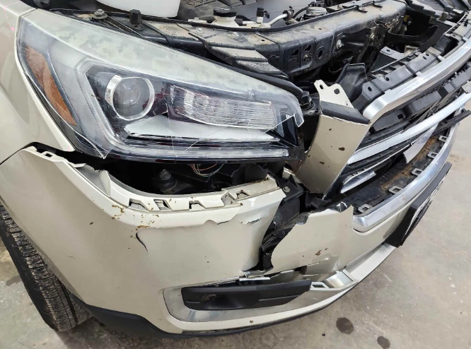 Damaged white car front end with a crushed bumper and exposed engine components