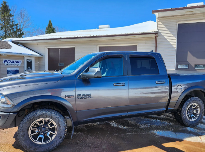 Blue-gray pickup truck parked in front of a house on a snowy day