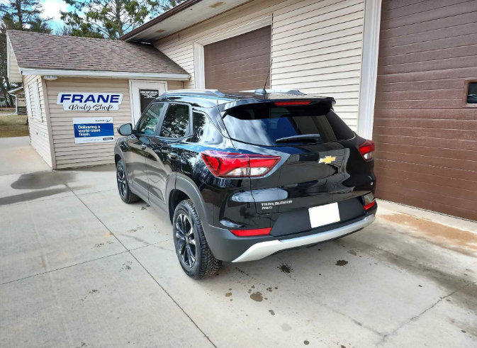 Black SUV parked beside a garage at a Frane dealership/service building.