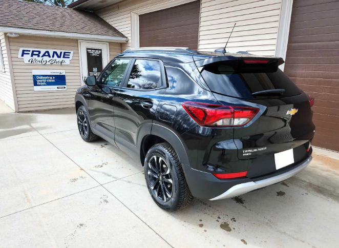 Black SUV parked in a driveway beside a garage with a Frane sign on the wall