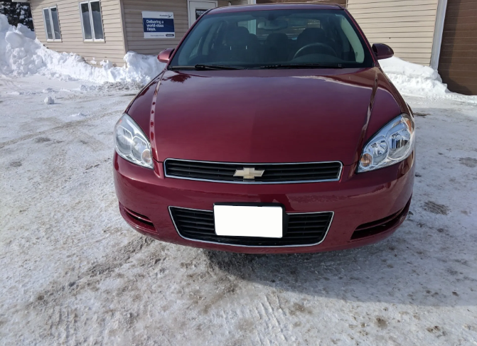 Maroon Chevrolet sedan parked on a snowy driveway in front of a building