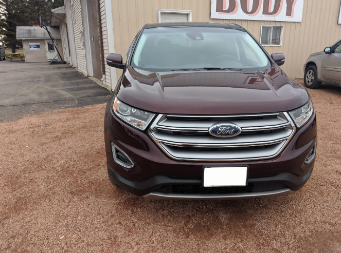 Maroon Ford SUV parked outside a body shop building