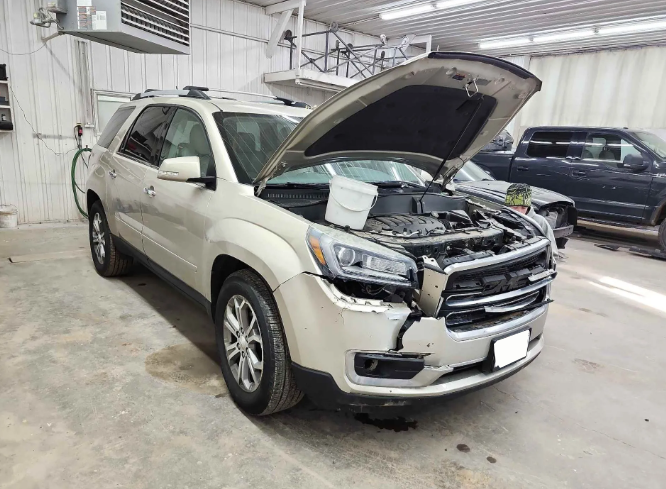 White SUV with hood open in an auto repair shop, showing front-end damage