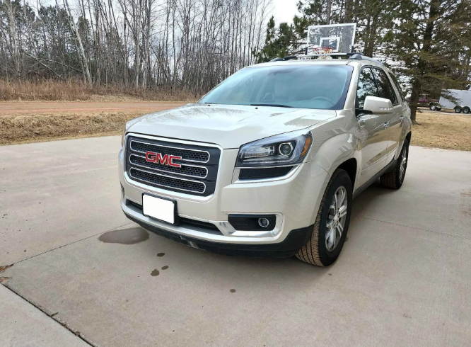 White GMC SUV parked on a driveway with trees in the background