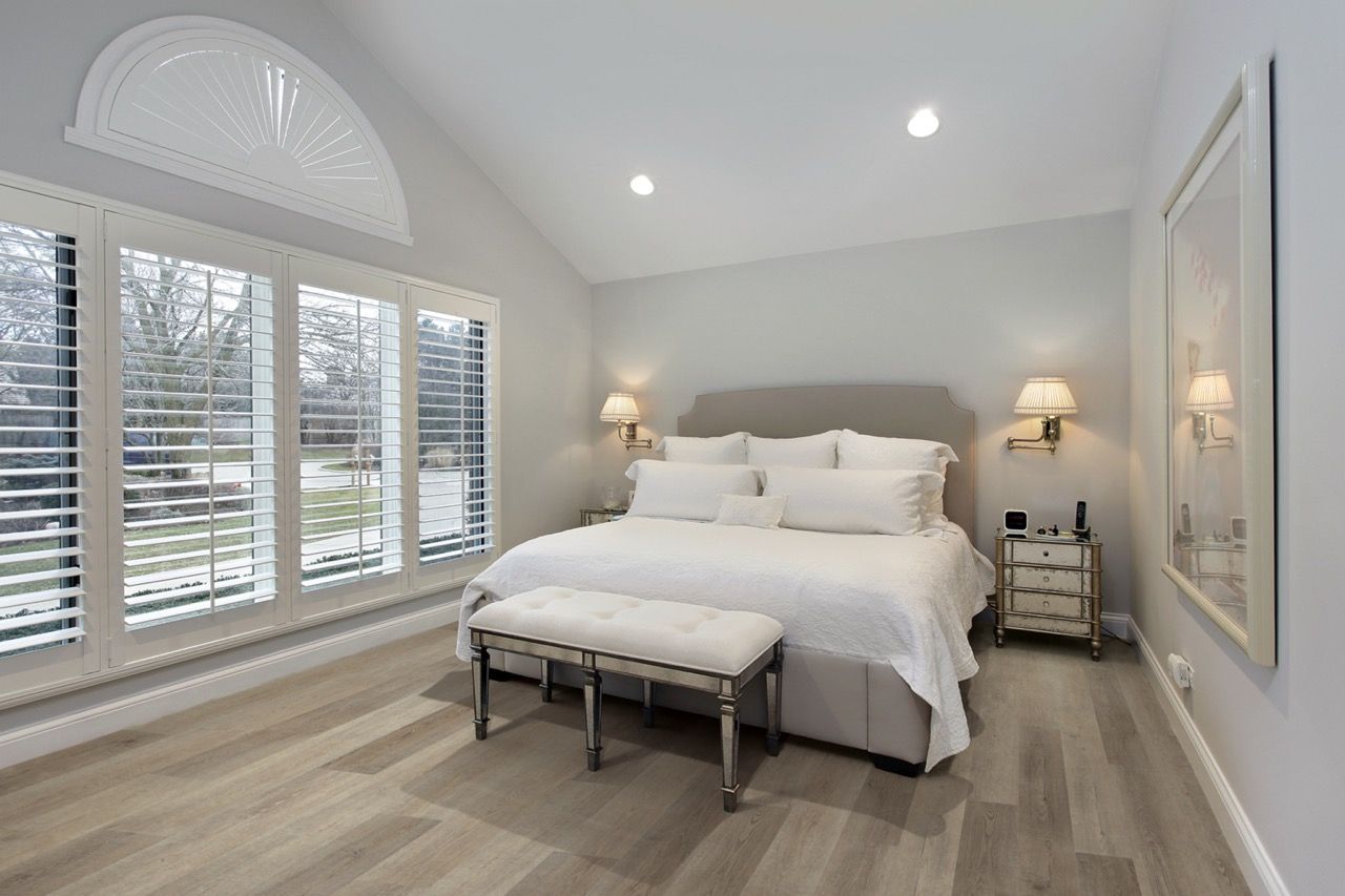 a bedroom with a large bed and lots of windows