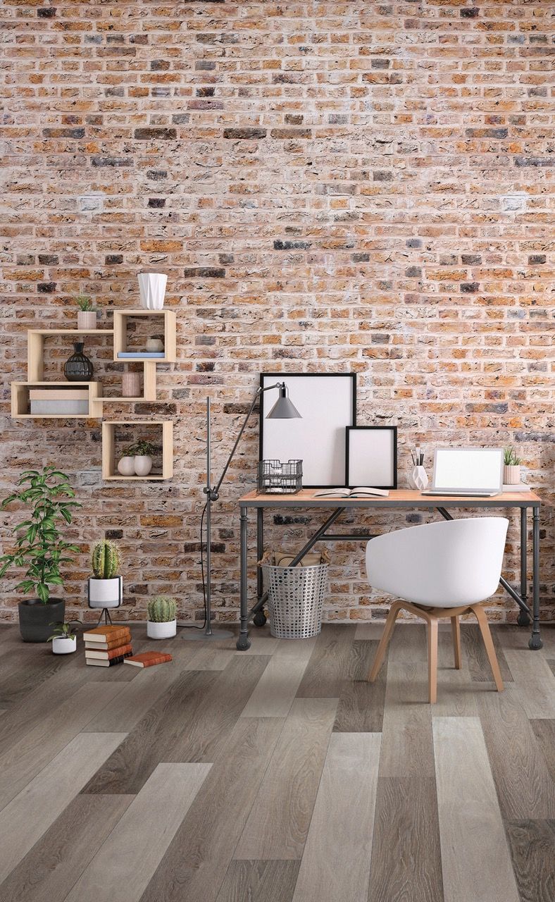 a room with a brick wall and a desk with a laptop on it