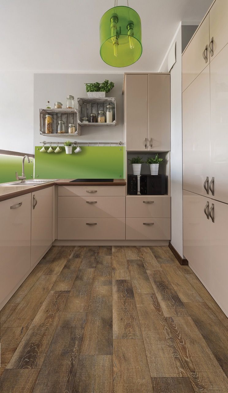 a kitchen with wooden floors, cabinets, a sink, and a green wall