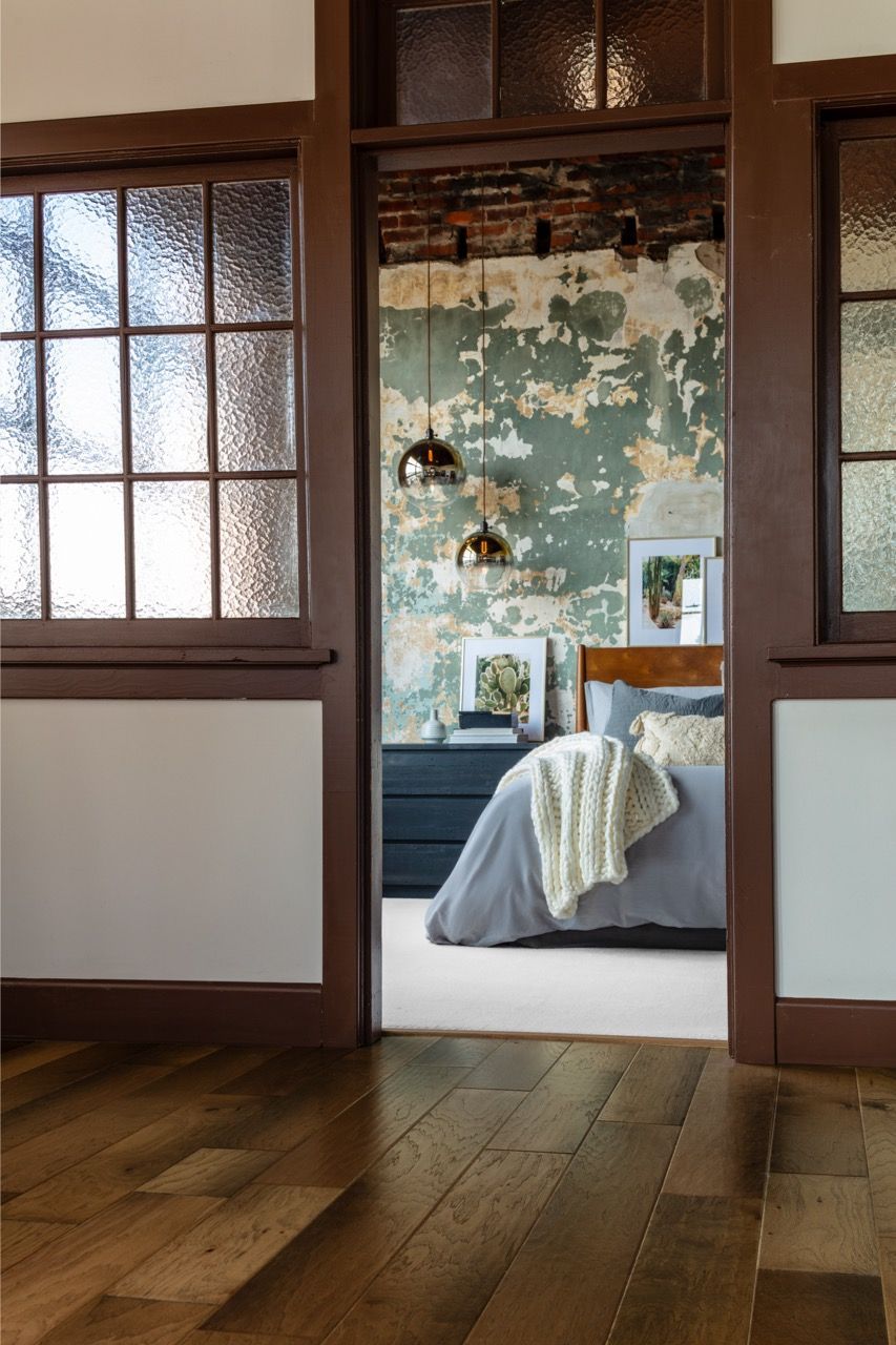 a bedroom with a bed and a window between two rooms