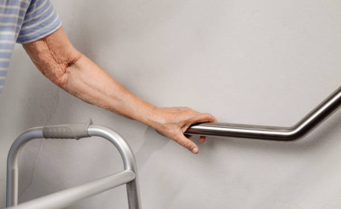 A person is holding onto a railing next to a walker.