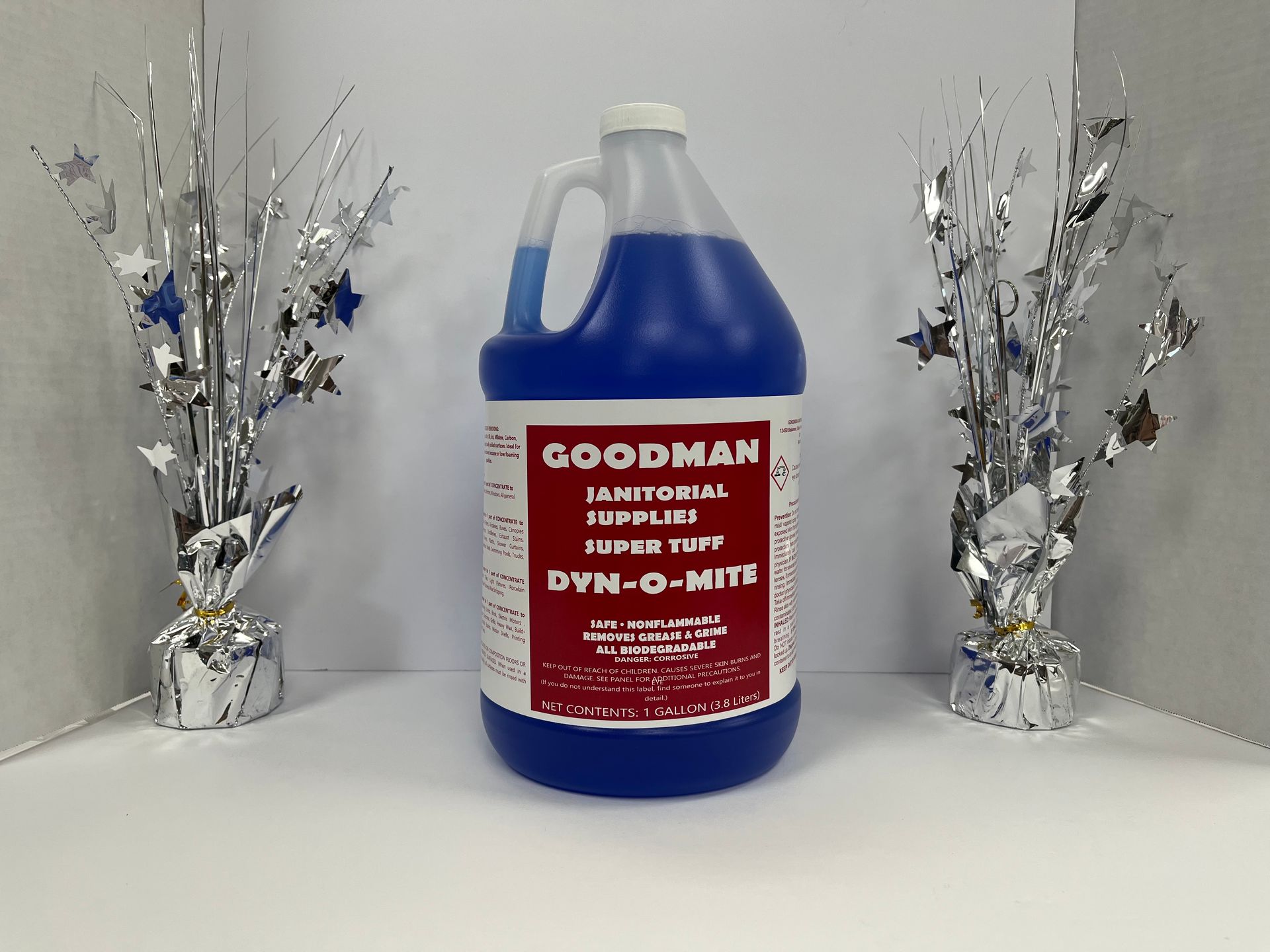 Blue Goodman antifreeze jug centered between two silver tinsel decorations on a white surface.