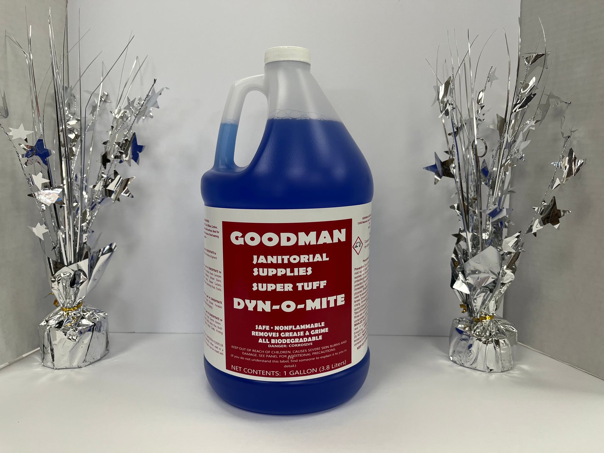 Blue Goodman Jamboree 3-in-1 cleaning jug centered between silver decorative trees on a white background