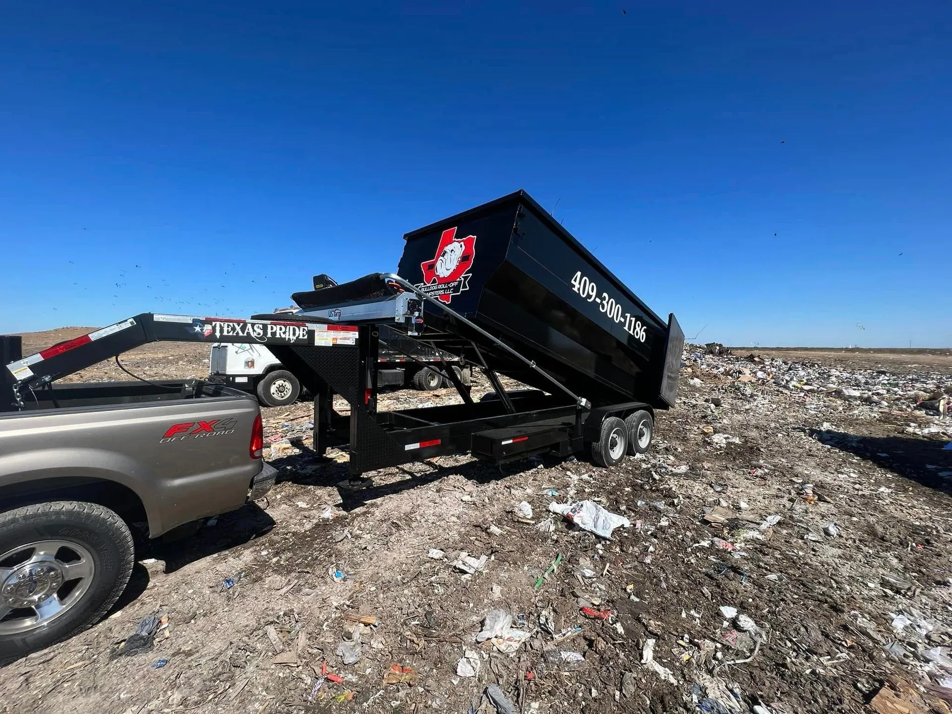 A dumpster is being towed by a truck in a dumpster.