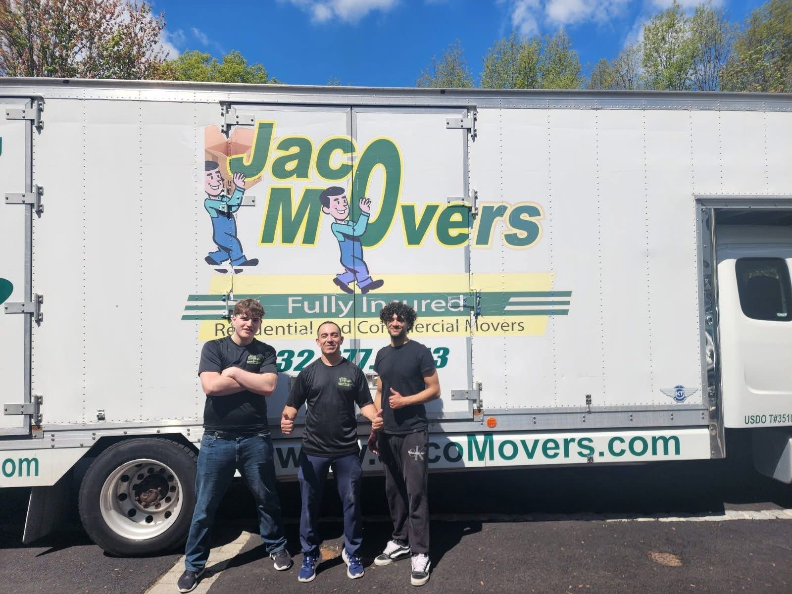 Three movers posing in front of a white Jac Movers truck on a sunny day.