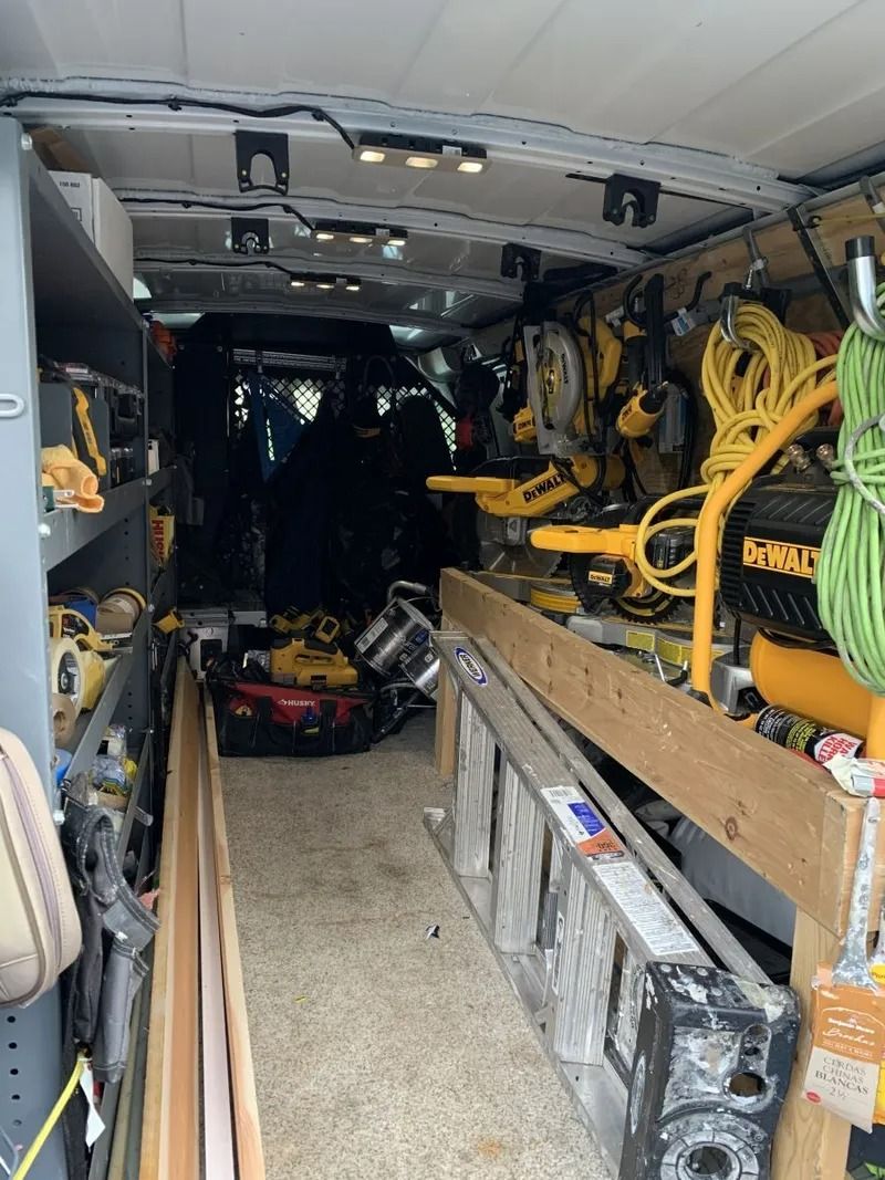 Inside of a work trailer, tools and equipment are organized on shelves and walls.