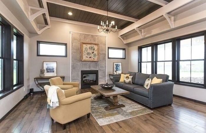 Living room with gray sofa, tan armchairs, fireplace, and hardwood floors.