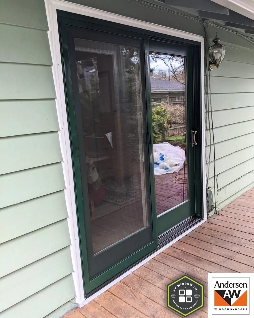 Green sliding glass door on a light green house with white trim. The door is closed, showing a screen on the left side.