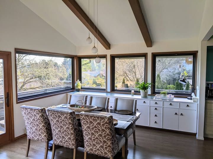 Dining room with table, chairs, windows, and built-in white cabinets. Light streams in.