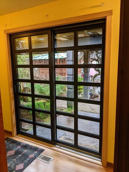 Sliding glass doors with black grids and wooden trim, opening onto a garden patio.