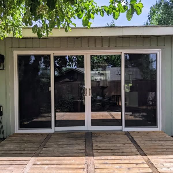 Exterior view of sliding glass doors with white frames and a wooden deck.