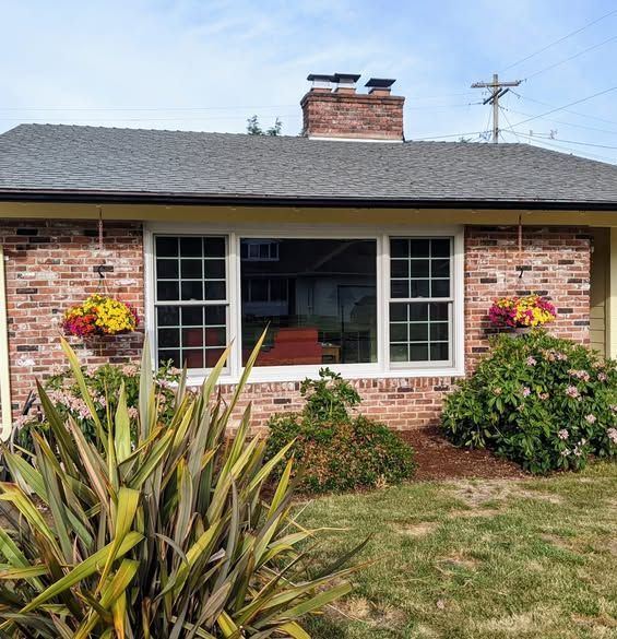 House exterior with brick, windows, flower boxes, chimney, and garden.