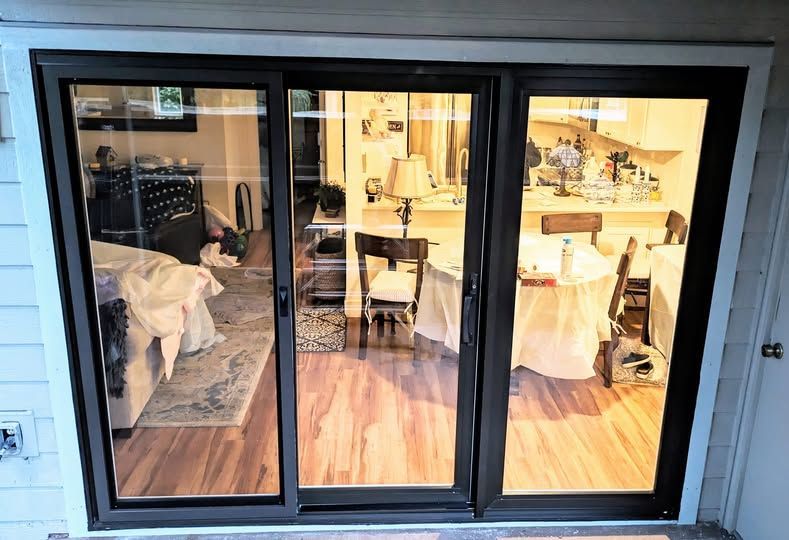 Black framed sliding glass doors open to a living space with warm interior lighting.