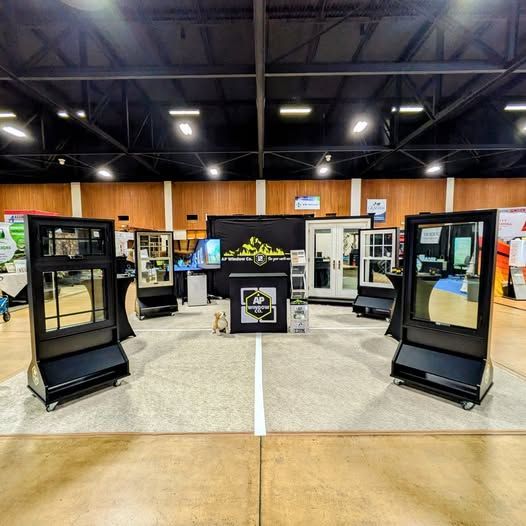 Trade show booth featuring window displays, with black and white frames, on a concrete floor.