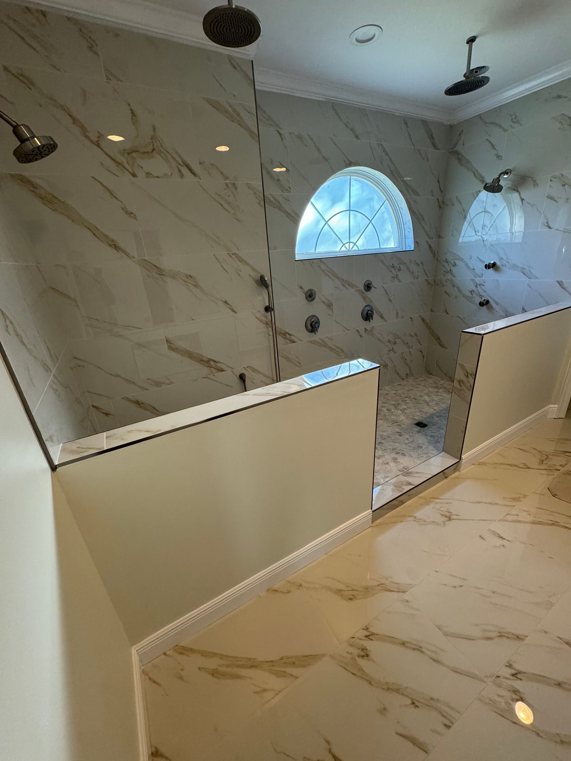 A bathroom with a walk in shower and a window.
