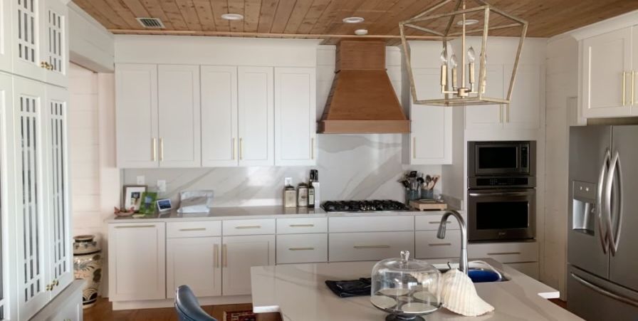 A kitchen with white cabinets , stainless steel appliances and a wooden ceiling.