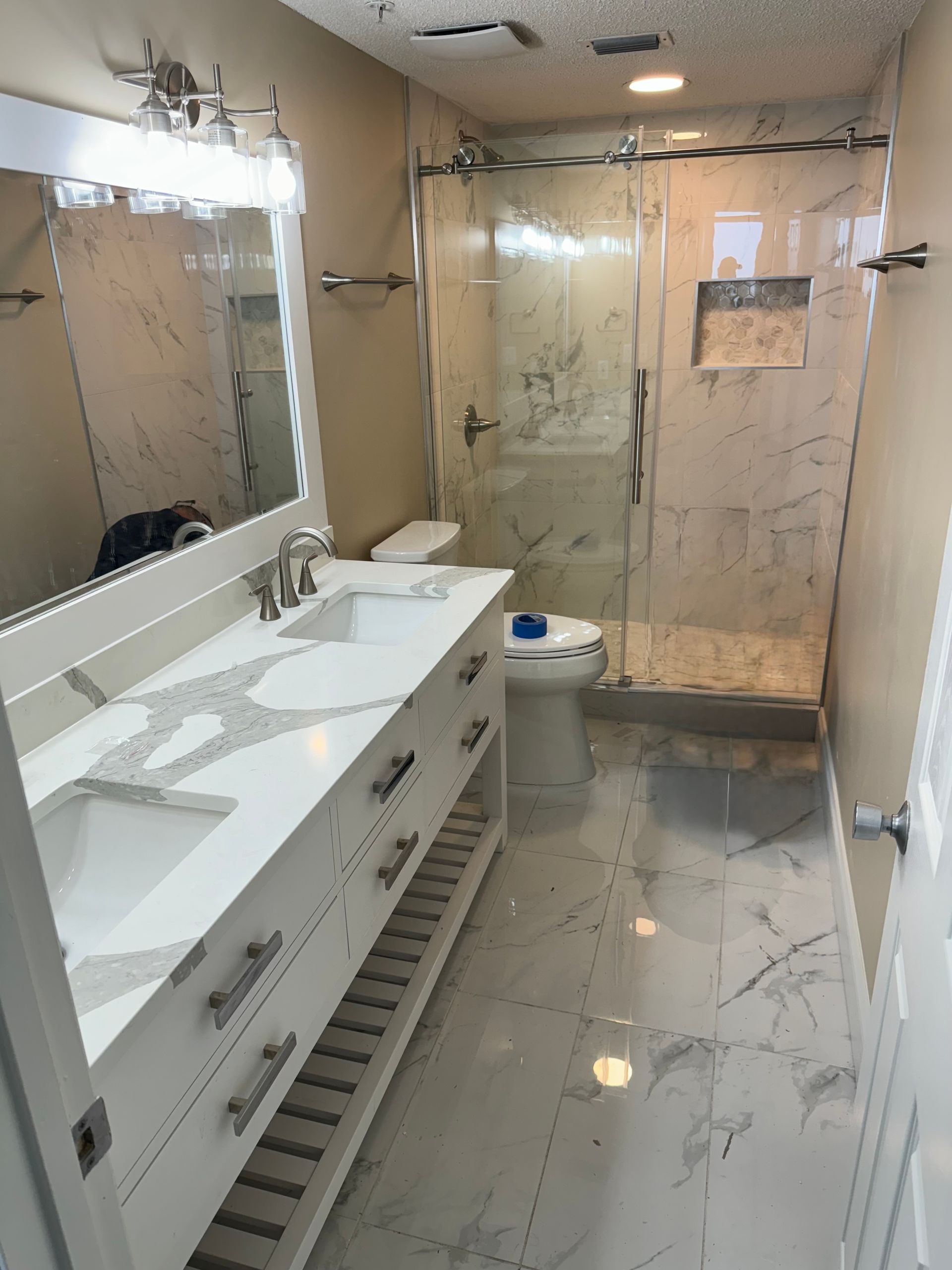 A bathroom with a sink , toilet , shower and mirror.