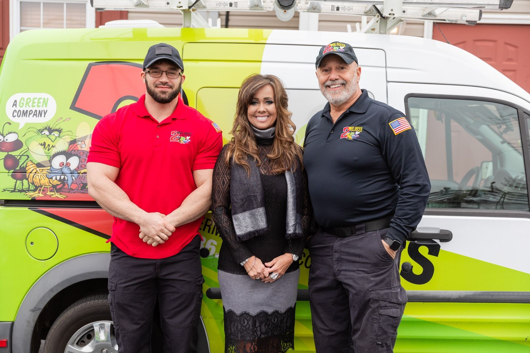 Three people stand in front of a green van. The van has cartoon graphics and the name