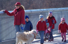 Woman with a dog and some kids on the walkway.