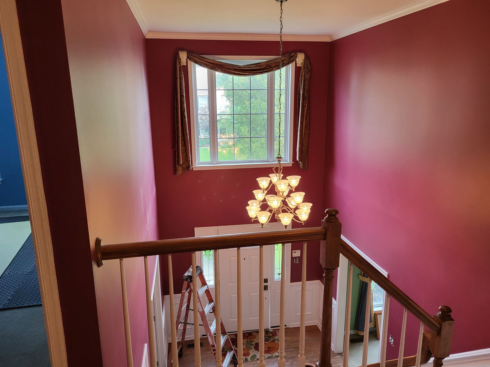 A staircase with red walls and a chandelier hanging from the ceiling.