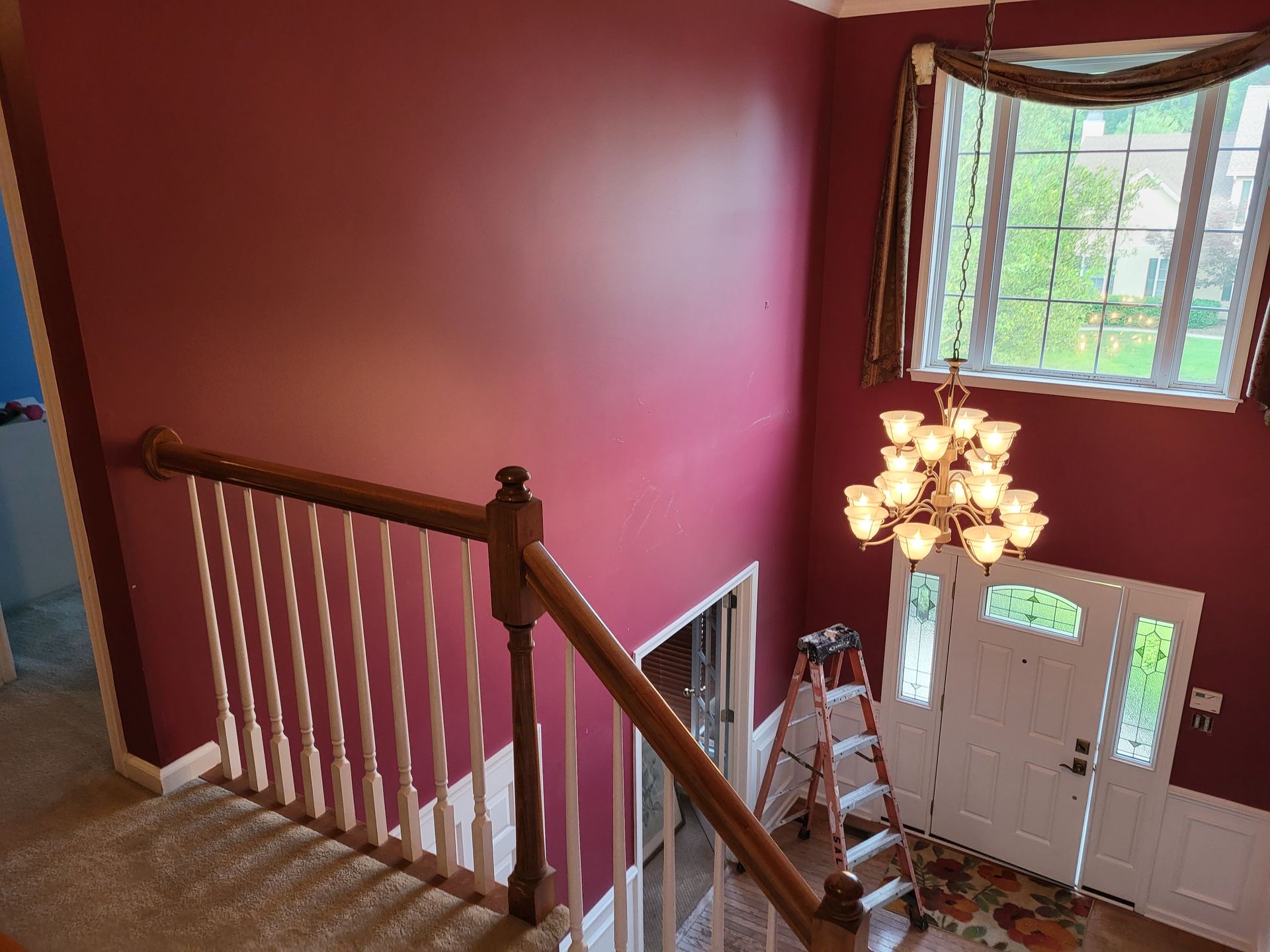 A man is painting the walls of a house with a ladder.