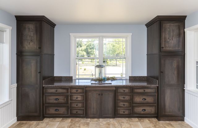 A kitchen with a sink , cabinets , drawers and a window.