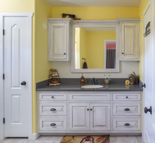 A bathroom with white cabinets and a large mirror