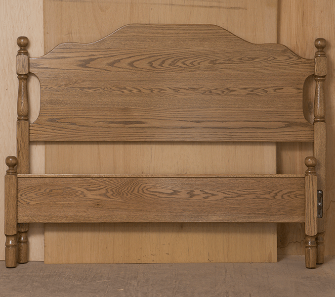 A wooden headboard is sitting in front of a wooden wall