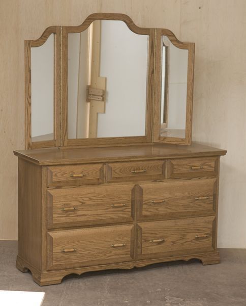 A wooden dresser with three mirrors on top of it