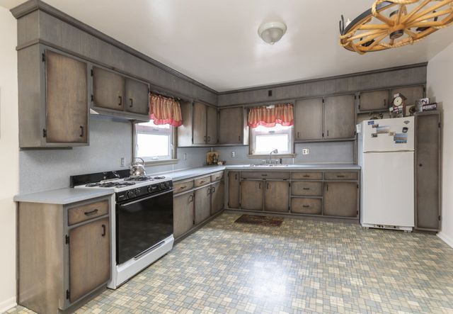 A kitchen with a stove , refrigerator , sink and cabinets.
